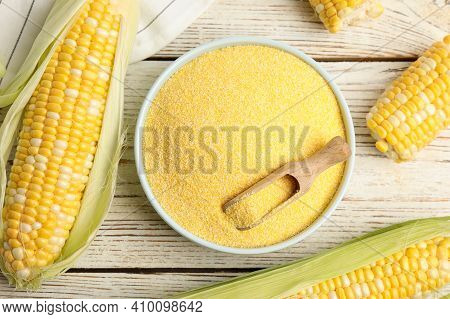 Cornmeal In Bowl And Fresh Cobs On White Wooden Table, Flat Lay