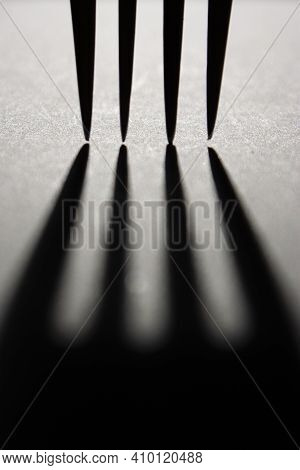 Vertical Conceptual Monochrome Picture With Contour Light Of A Dinner Fork Tines Silhouettes, Castin
