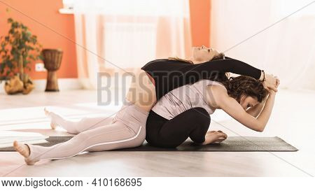 Two Women In Sportswear Practicing Yoga Doing Upavishta Konasana Bending And Baddha Konasana Bending