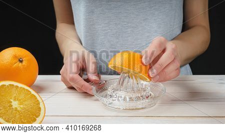 Young Woman Squeezes Orange Juice Using A Manual Glass Juicer
