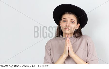 Beautiful Woman Keeps Palms Pressed Together In Front Of Her, Pouts Lips, Has Regretful Or Sorrorful