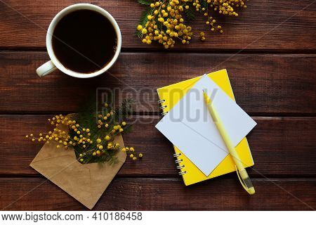 Cup Of Coffee, Mimosa Flowers, Yellow Notepad, Empty Paper Blank And Pen On Wooden Background. Rusti