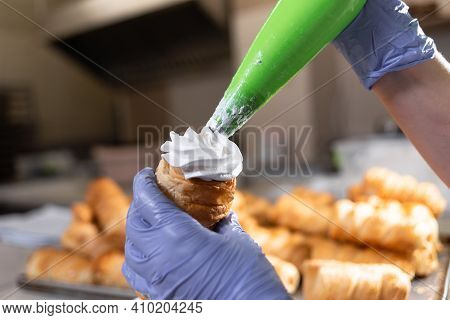 The Hands Of The Pastry Chef Fill A Tube Of Sweet Puff Pastry With Whipped Egg Whites And Custard. S