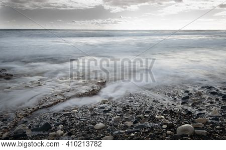 Seawaves Splashing To The Coast With Pebbles Against Stormy Dramatic Cloudy Sky. Wintertime, Longexp