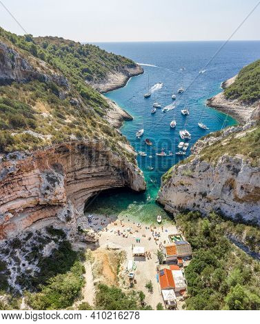 Aerial Drone Shot Of Tourists Swim Sunbath At Stiniva Cove Beach Of Adriatic Sea On Vis Island In Cr