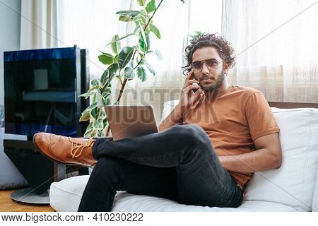 Leisure Activity Of A Indian Guy With Sunglasses Dressed In Casual Attire Posing On Sofa With A Lapt