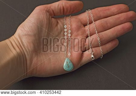 A Pendant Made Of Natural Stone Turquoise Silver Chain Lies On A Woman's Hand. Author's Jewelry From