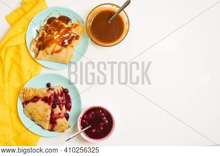 Blini Pancakes With Red Berry Jam Close-up On A Blue Plate On A Light Background . Traditional Russi
