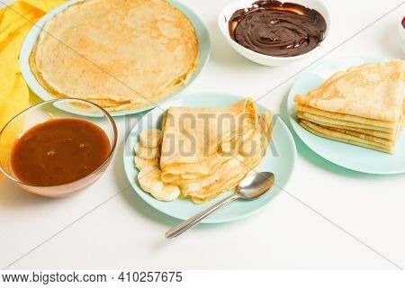 Blini Pancakes With Banana And Caramel, Close-up On A Blue Plate On A Light Background . Traditional