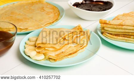 Blini Pancakes With Banana And Caramel, Close-up On A Blue Plate On A Light Background . Traditional