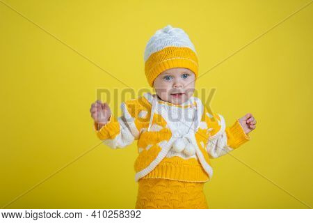 Little child one year age girl in yellow clothes will be surprised waving hands on a yellow background expresses emotions
