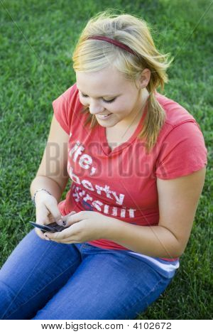 テキスト メッセージの草の上に座って笑顔の女の子