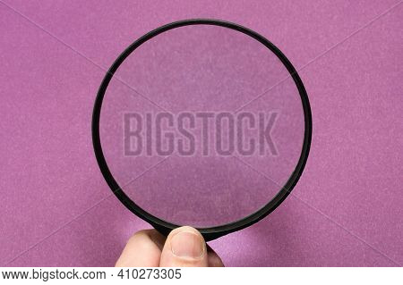 Magnifying Glass On A Fiolet Background. Hand With Magnifying Glass