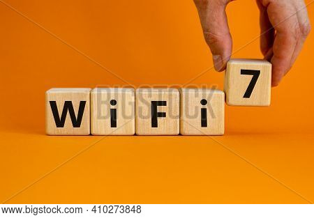 Wifi 7 Symbol. Businessman Holds A Wooden Cube With Words Wifi 7. Beautiful Orange Background, Copy 