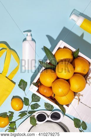 Fresh Citrus Fruits In A Wooden Box, A Summer Accecories And Cosmetics Bottle On A Blue Background