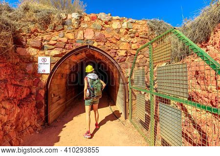 Back Of Tourist Girl With Miners Helmet Walking Inside Tunnel Cave Of Battery Hill Mining Center. To