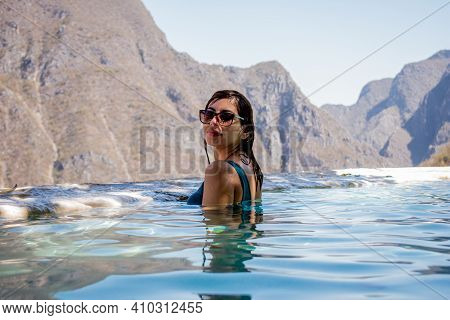 Beautiful Woman In A Blue Swimsuit In The Water In Front Of A Huge Mountains In A Grotto In Tolanton