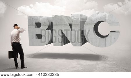 Rear view of a businessman standing in front of BNC abbreviation, modern technology concept