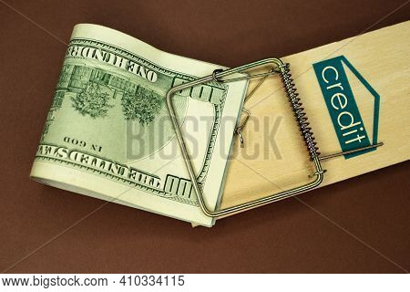 Mousetrap With Money. Dollars And The Inscription: Credit. Brown Background. Wooden Mousetrap