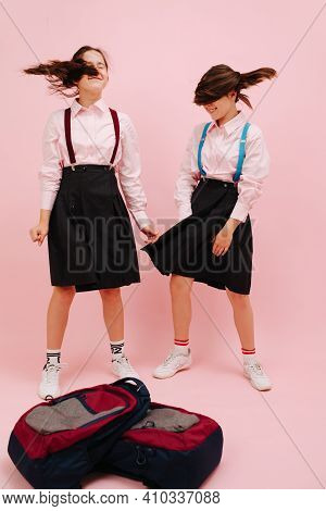 Happy Little Twin Schoolgirls With Twintails Shaking Heads. Low Angle. Over Pink