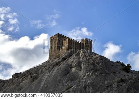 The Tower Of The Genoese Fortress. View From Below Against The Cloudy Sky In The Afternoon. Sudak, C