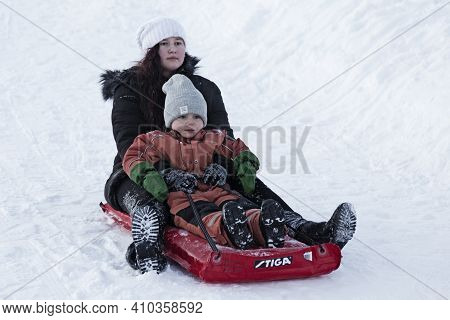 Umea, Norrland Sweden - February 11, 2021: Big Sister And Little Brother Go Sledding Together