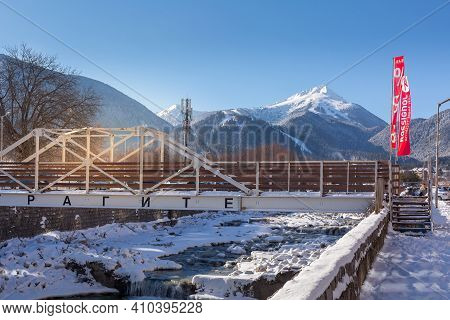 Bansko, Bulgaria - January 28, 2021: Glazne River In Bulgarian Town, Bridge And Snow Pirin Mountains