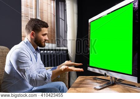 A Young Man Gesticulating In Front Of Tv At Home, Confused, Does Not Understand . Puzzled Programmer