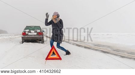 Angry Young Woman Is Talking On A Mobile Phone, Waving Her Hands In Anger Near A Warning Road Sign: