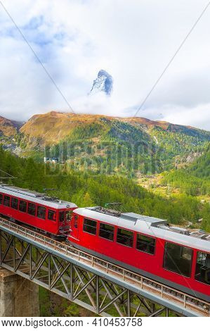 Zermatt, Switzerland. Gornergrat Red Tourist Train On The Bridge And Matterhorn Panorama In Swiss Al