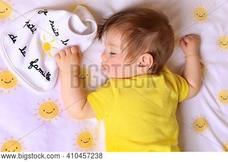 A Baby Holding A Bib Saying That He's The Little Sun Of The Family In French.