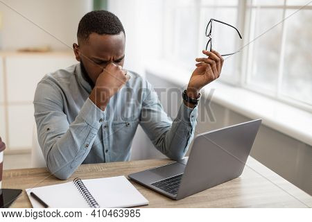 Eyes Fatigue. Tired African Businessman Holding Eyeglasses Massaging Nosebridge After Work On Comput