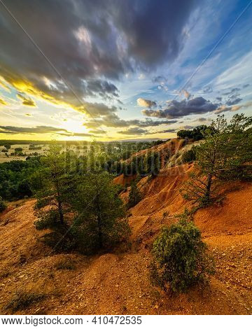 Sunset Landscape In The Field, Trees, Red Earth And Sky With Big Clouds In Blue And Orange Tones Of 