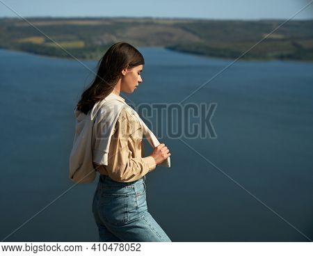 Charming Young Woman With Brown Hair Standing On Top Of Mountain And Looking At Bakota Bay. Amazing 