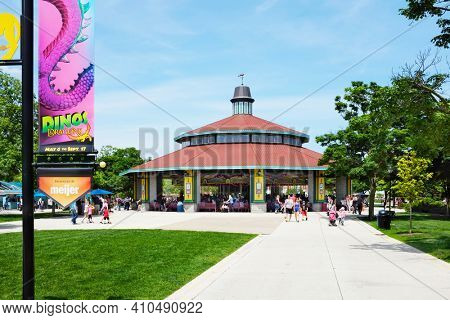 BROOKFIELD, ILLINOIS - MAY 27, 2017: The Carousel at Brookfield Zoo. The ride is popular attraction of the park with families and children. A banner announcing the Dinos Exhibit is in the foreground.