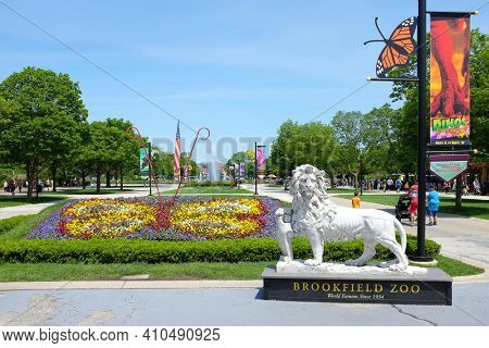 BROOKFIELD, ILLINOIS - MAY 27, 2017: Lion Statue at the Brookfield Zoo South Gate. Roosevelt Fountain and the Carousel are in the background