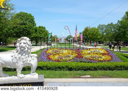 BROOKFIELD, ILLINOIS - MAY 27, 2017: Lion Statue at the Brookfield Zoo South Gate. Roosevelt Fountain and the Carousel are in the background