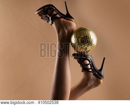 Sexy Woman Legs. Disco Party Event. Woman High Heels With Gold Disco Ball. Celebrating Background
