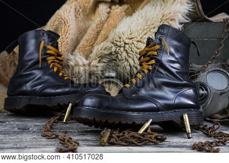 Leather Boots With Rusted Chains And Bullet Shells With Military Gas Mask And Fur Coat In Background