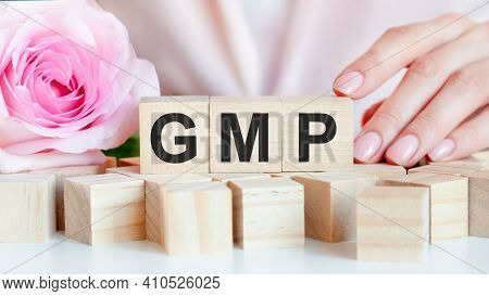 A Woman Holds A Wooden Cube With The Text Gmp In Her Hand. On The Wooden Cubes There Is A Living Ros