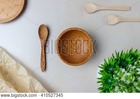 Wooden Utensils On The Kitchen Table. Round Wooden Plates, A Wooden Spoons, A Green Plant. The Conce