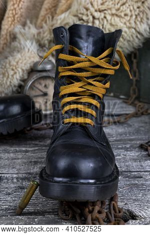 Leather Boot With Rusted Chains And Bullet Shells With Military Gas Mask And Fur Coat In Background