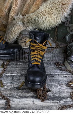 Leather Boot With Rusted Chains And Bullet Shells With Military Gas Mask And Fur Coat In Background