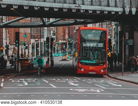 London Uk January 2021 View Of A Double Decker London Bus Passing Under A Train Bridge. People Walki