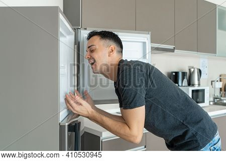 On A Hot Day, The Guy Cools With His Head In The Refrigerator. Broken Air Conditioner