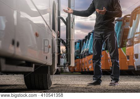 Caucasian Bus Driver In His 40s Welcoming Passengers While Staying And Welcoming Next To Tour Bus Do