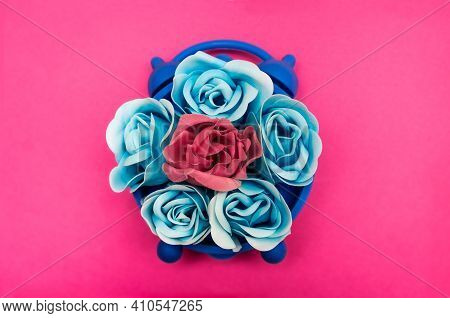 Blue And Pink Rose Flowers In A Blue Clock On A Pink Background