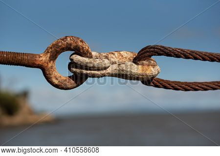 Traditional, Old, Rusty Turnbuckle At A Pier, Viewed From Close, Against Blue Sky And Ocean