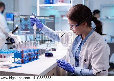 Concentrated Professional Woman Scientist In Laboratory Working With A Micropipette And A Dropper. B