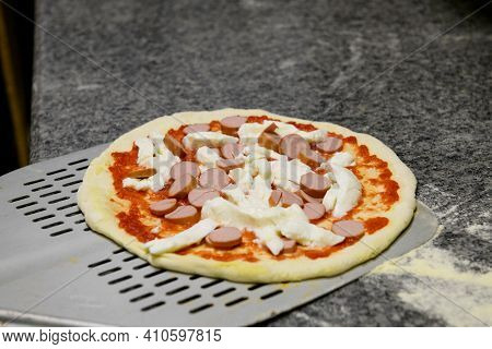 A Fresh Margherita Pizza With Sauseges On A Shovel, Ready For Baking, Close Up